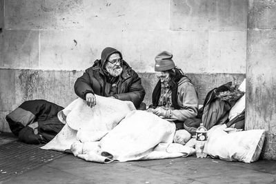 Beggars sitting on footpath against wall