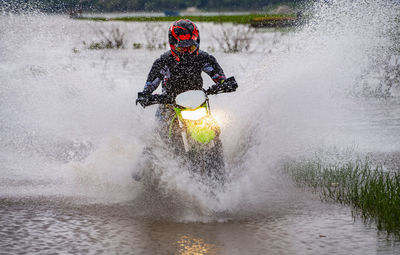 Woman riding her dirt-bike through a lake near pak chong / thailand