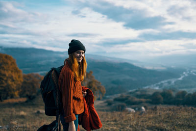 Young woman standing on mountain against sky