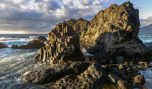 Rock formation on beach against sky