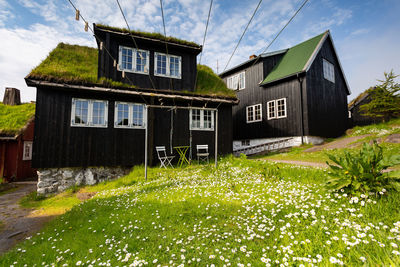 House amidst plants and building against sky