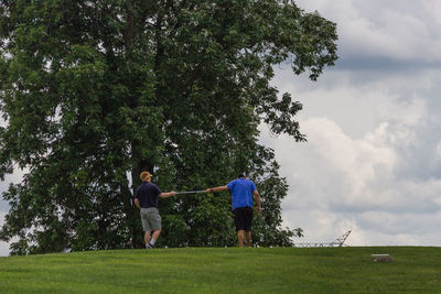 People standing on golf course against sky