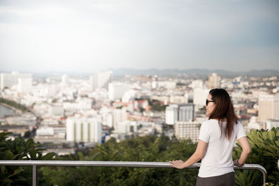 Woman standing on railing against cityscape