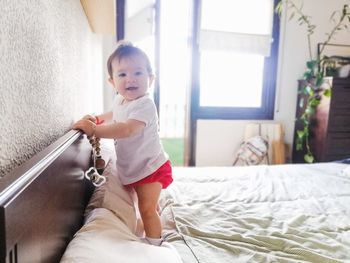 Baby standing up for the first time on the bed.