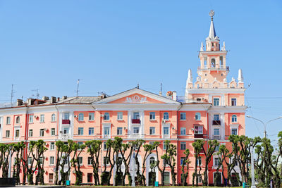 Pink building with spire against blue sky. this is unofficial symbol of komsomolsk-on-amur in russia