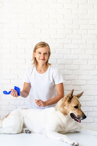 Portrait of woman with dog against white wall