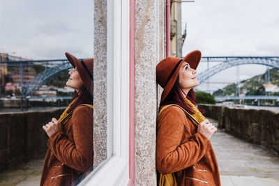 Woman wearing hat against sky in city