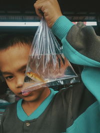 Close-up portrait of boy holding fish in plastic bag