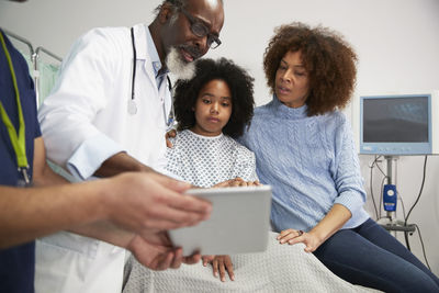 Doctor discussing treatment over tablet pc with patient and mother at hospital