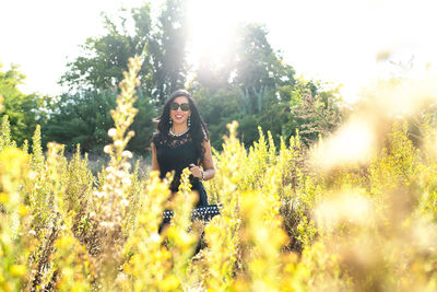 Woman standing on field against trees