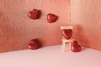 Red glowing hearts and chair in corner on shiny background. anniversary and valentine's day 
