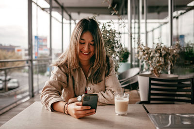 Mexican woman chats with friends, enjoys morning coffee on cafe terrace. digital life, slow living