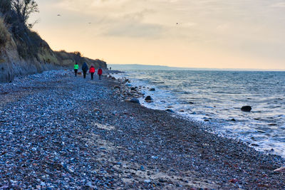 People on beach against sky during sunset