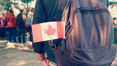 Midsection of backpack man with canadian flag on footpath