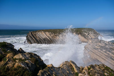 Scenic view of rocks in sea against clear sky