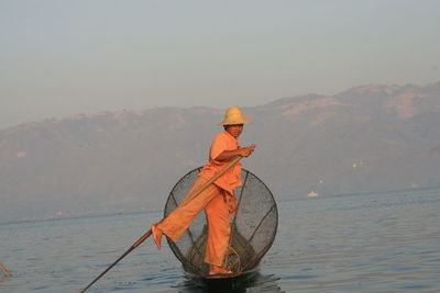 Full length of fisherman fishing in lake at sunset