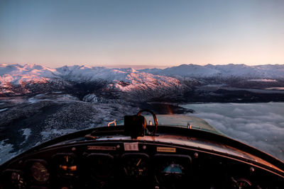 Scenic view of snow covered landscape seen through helicopter window against sky