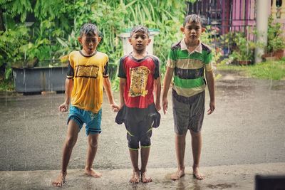Portrait of boys standing on footpath during rainy season