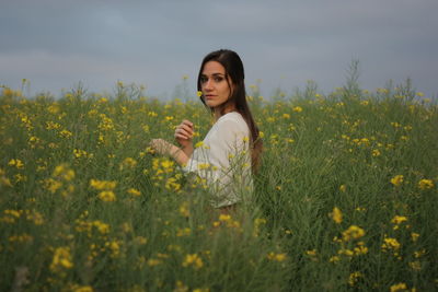 Portrait of young woman standing amidst plants