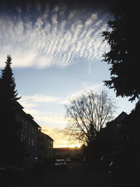 Cars on street amidst buildings against sky during sunset