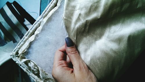Cropped hand of woman holding fabric at home