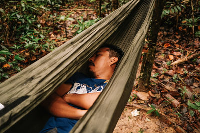 Portrait of man relaxing on hammock in forest