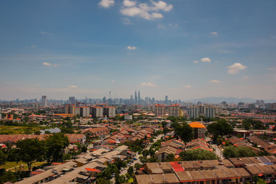 Distant view of petronas towers and kuala lumpur tower in city against sky