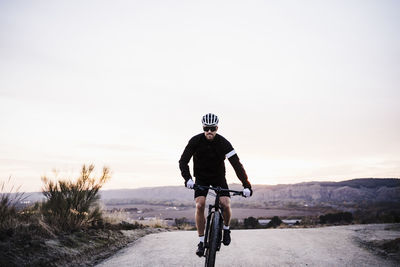 Man riding bicycle on road against clear sky