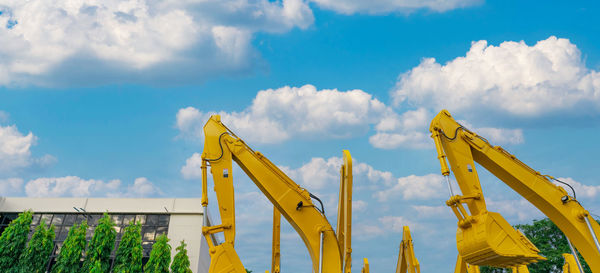 Yellow backhoe with hydraulic piston arm against blue sky. huge bulldozer parked at parking lot.