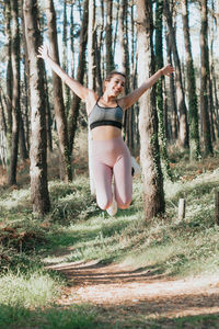 Full length of young woman exercising on field