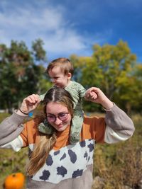 Portrait of smiling girl with arms outstretched standing against trees