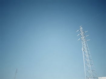 Low angle view of communications tower against clear blue sky