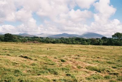 Scenic view of fields against cloudy sky