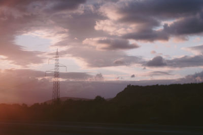 Silhouette electricity pylon against sky during sunset