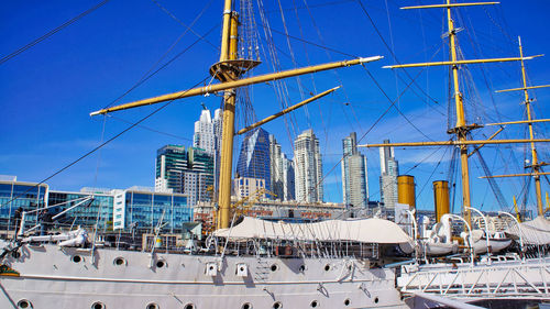 Sailboats moored in city against clear blue sky