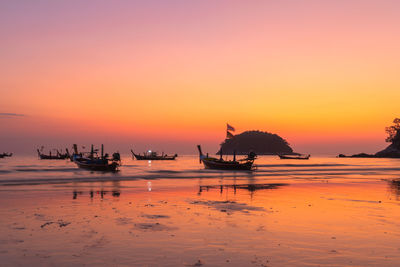 Silhouette boats in sea against orange sky