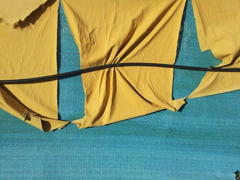 blue, textile, fabric, nautical vessel, umbrella, one person, part of, outdoors, day, rope, sailboat, multi colored, flag, transportation, close-up, nature, waterfront, travel, boat, canvas