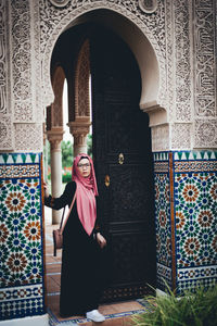 Portrait of woman standing at entrance of historic building