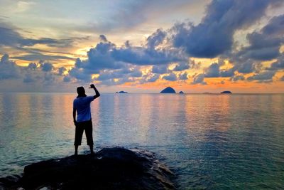 Rear view of man standing at beach against sky