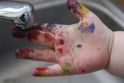 Cropped image of child with painted hand at sink