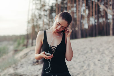 Woman listening music while standing at beach