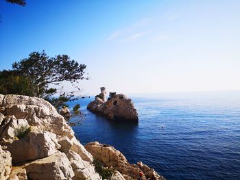 Rocks on sea against blue sky