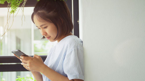 Side view of young woman using mobile phone