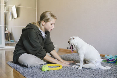 Girl playing with disabled pet dog sitting at home