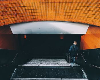 Rear view of man with luggage moving down steps at underground walkway