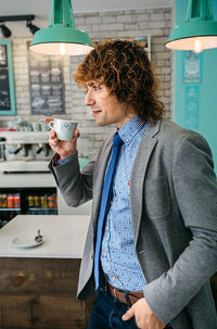 Businessman having coffee while standing in cafe