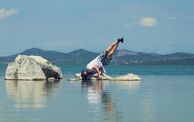 Rear view of man surfing in sea against sky