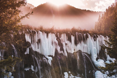 Scenic view of waterfall against sky during sunset
