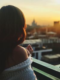 Rear view of woman with umbrella against sky during sunset