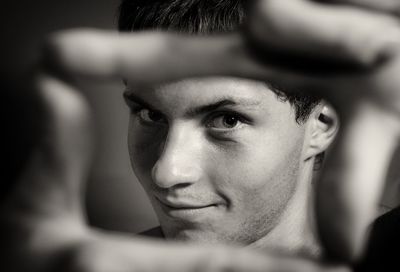 Close-up of young man making frame with his fingers at home